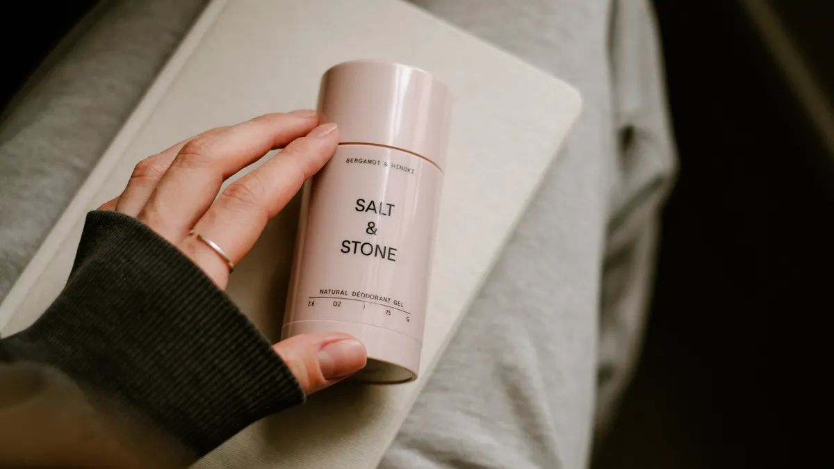 How to switch to natural deodorant Hand holding a Salt & Stone deodorant stick